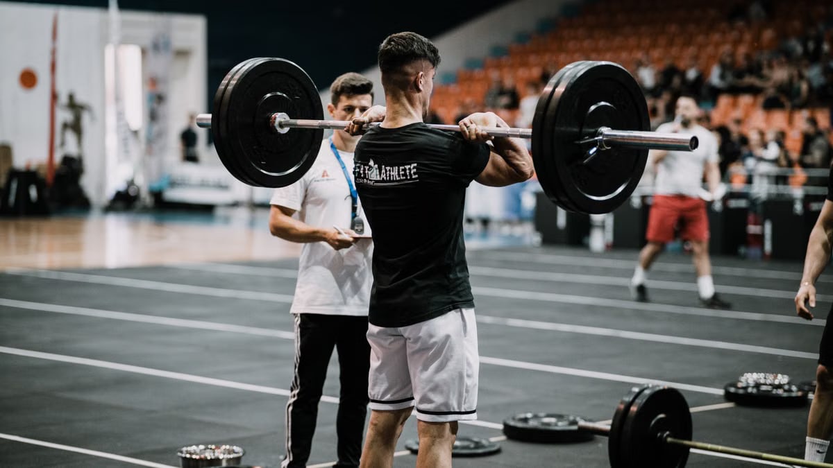 An athlete performs a challenging lift during a weightlifting competition indoors.